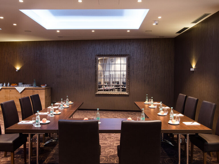 Der Meetingraum im Hotel Oswald mit stilvollem Ambiente, dunklen Holztischen und bequemen Stühlen für produktive Besprechungen im Bayerischen Wald.
