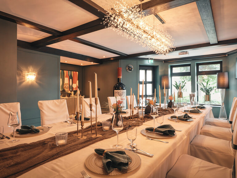 Das elegant eingerichtete Weinzimmer mit hell gedeckter Tafel unter raffinierter Beleuchtung im Hotel Oswald im Bayerischen Wald.
