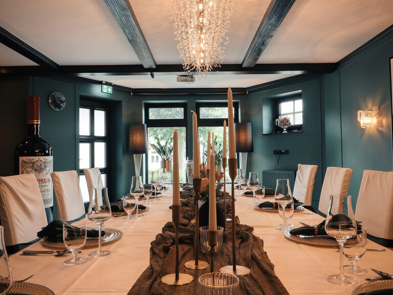 Der stilvoll gedeckte Tisch mit eleganter Tischdeko und Kronleuchter im Weinzimmer des Hotel Oswald.
