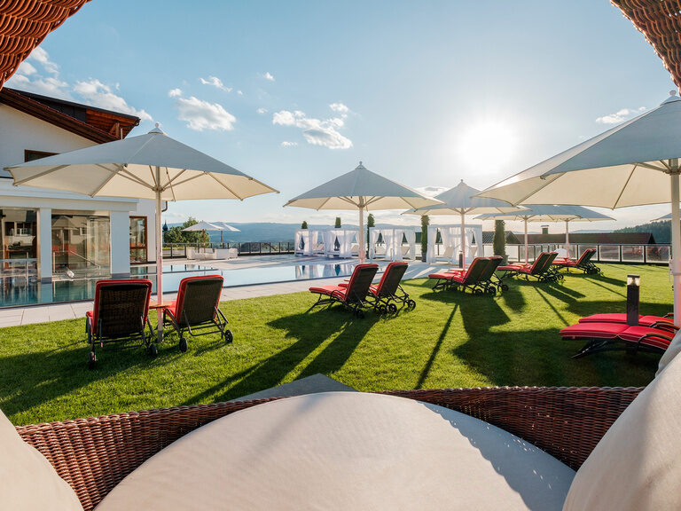 Die Sonne strahlt auf den Wellness-Garten mit Pool und Liegemöglichkeiten vom Hotel Oswald im Bayerischen Wald.