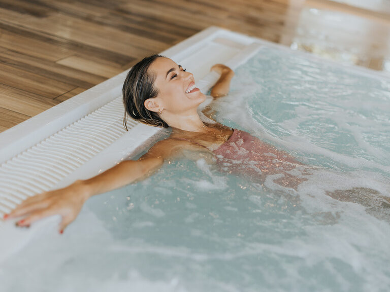 Frau entspannt im sprudelnden Whirlpool im Hotel Oswald Bayerischen Wald.