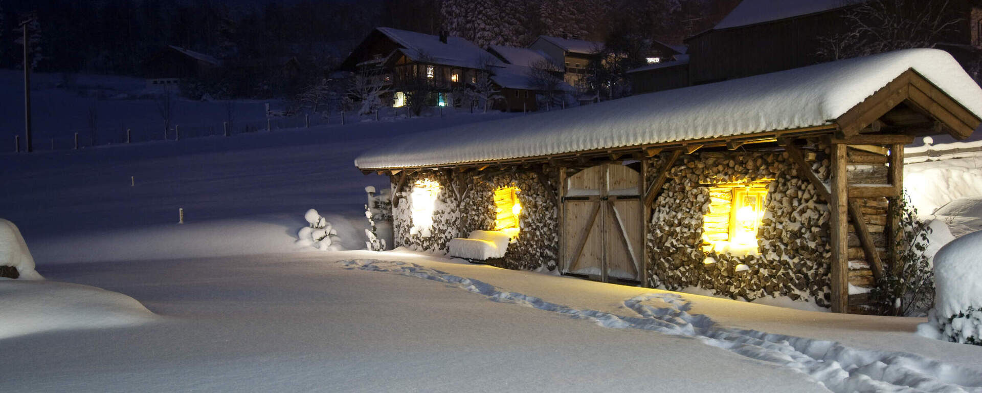 Winterliche Hütte bei Nacht im Hotel Oswald Bayerischer Wald mit Schnee und stimmungsvollem Licht.