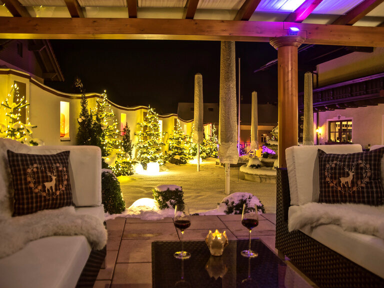 Die festlich dekorierte Winterlounge im Wellnesshotel Oswald lädt zum Verweilen bei Kerzenschein und Blick auf den verschneiten Innenhof ein.