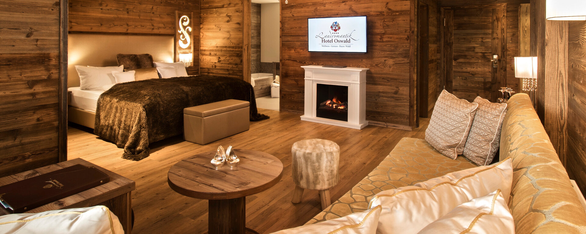 Der kombinierte Wohn- und Schlafbereich der Top Suite Storchennest Plus im Hotel Oswald Bayerischer Wald – mit Kuschelsofa, Kamin und Design-Akzenten.