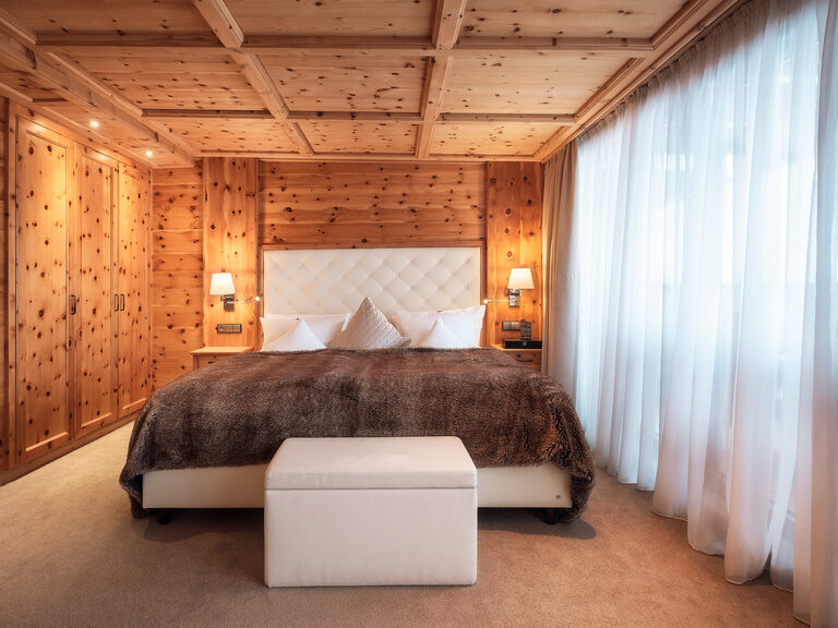 Das Zirbenzimmer Abendrot im Hotel Oswald eine Oase aus duftendem Zirbenholz mit weichen Teppichen, flauschigen Decken und einer gemütlichen Sitzecke.